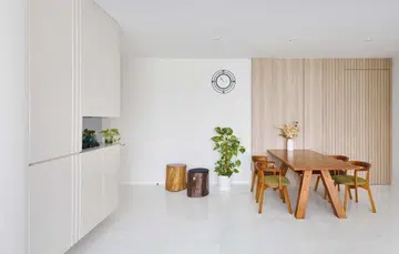An all-white and wood dining area for a couple in their 60s and their son lives in this 1,550 sqft 3-bedroom condominium apartment in Keppel Bay. Interior design by Weiken.
