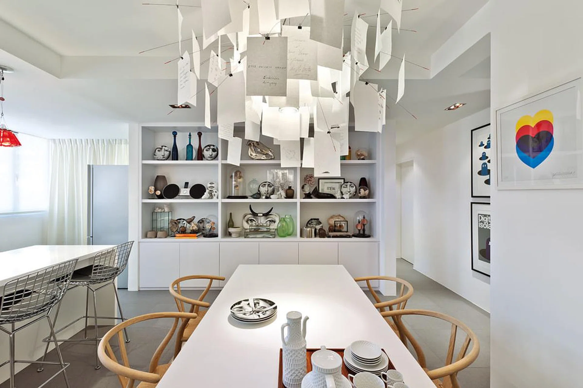 An extensive collection of Fornasetti plates and other ornaments lends a personal, quirky touch to the dining area and complements the austere white of the setting.