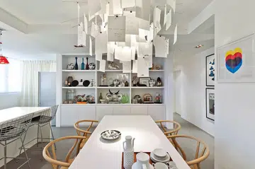 An extensive collection of Fornasetti plates and other ornaments lends a personal, quirky touch to the dining area and complements the austere white of the setting.