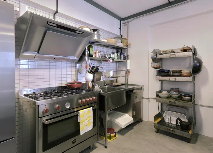 The massive gas stove is from Bertazzoni with fun red knobs. The extra deep basin, counters, shelves, and cooking hob are all restaurant-approved. 
