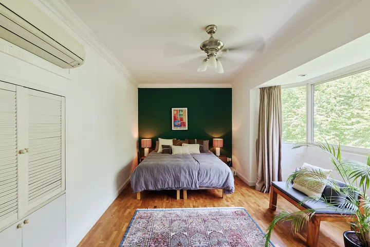Tucked away on the uppermost floor, the master bedroom pairs calming greenery views with a deep green feature  wall, creating a quiet retreat from the busier family spaces below.