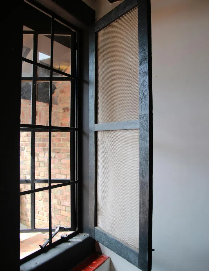 Black metal-frame windows are seen in Tudor-style houses, but those here had double-frame layers with netting to keep insects out.
