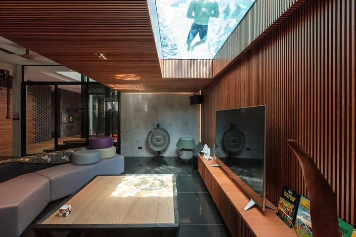 The basement also houses a large bar and entertainment area, which is partially lit by the glass-bottomed pool.