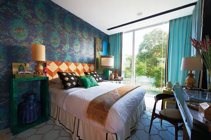 The Hermes wallpaper in twilight blue sets the mood for the master bedroom. The unfinished wood headboard in an orange diamond pattern injects colour and vibrancy, so the space doesn't seem too dark. The bedside tables each serve a different purpose - one is for bedtime reading, the other is for work.
