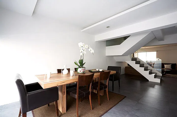 The long, slim custom-made dining table in this HUDC Maisonette unit in Hougang visually elongates the dining area. It’s wrapped in a wood-grain laminate.