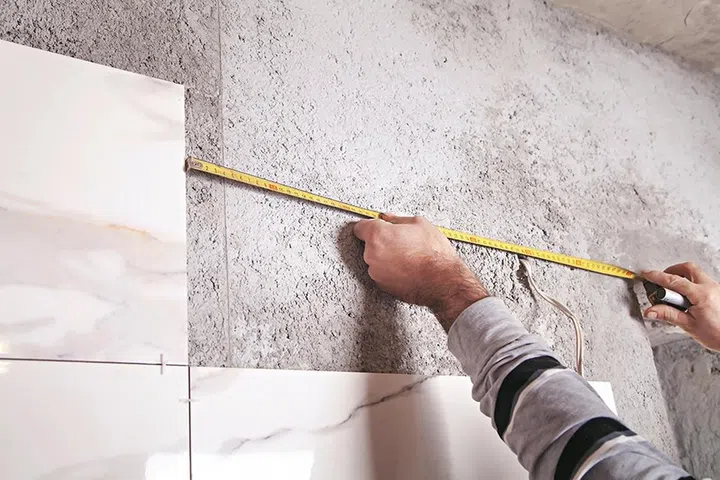Man measures the wall. Measures and cutting tile 