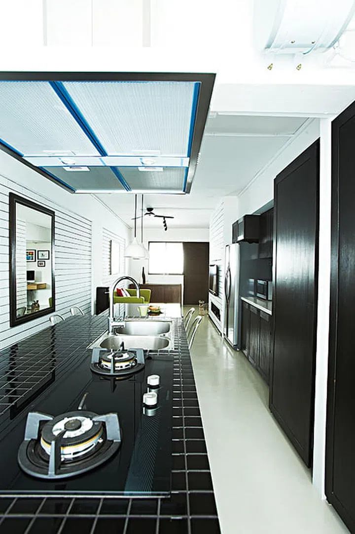 The kitchen’s cabinets are, in fact, much deeper than they look as they eat into the bedroom space behind. Interior design by Box.ID Studio
