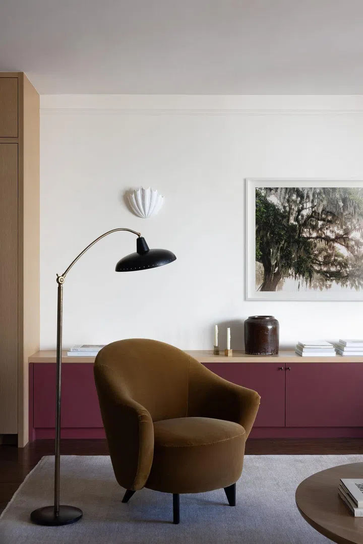 Deep brown armchair set against a maroon TV console. Living room with earthy colour palette and tones. Interior design by Innen Studio. Photo by Bess Friday. Styling by Austin Whittle.