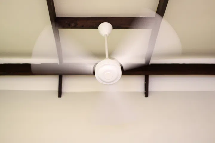 White electric ceiling fan in motion.