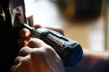 Hands drilling into a door lock