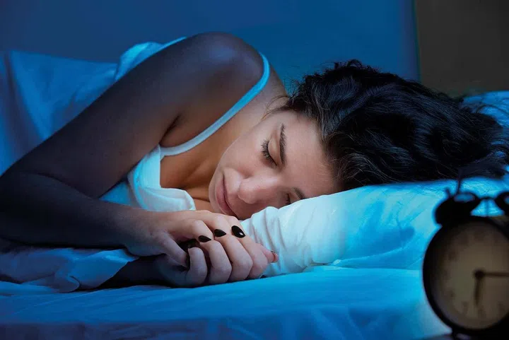 Woman sleeping in a bed in a dark bedroom (Image 123rf)