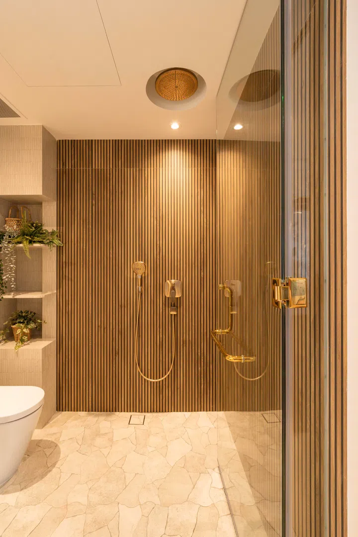 A glass door divides the vanity from the shower and toilet area.
