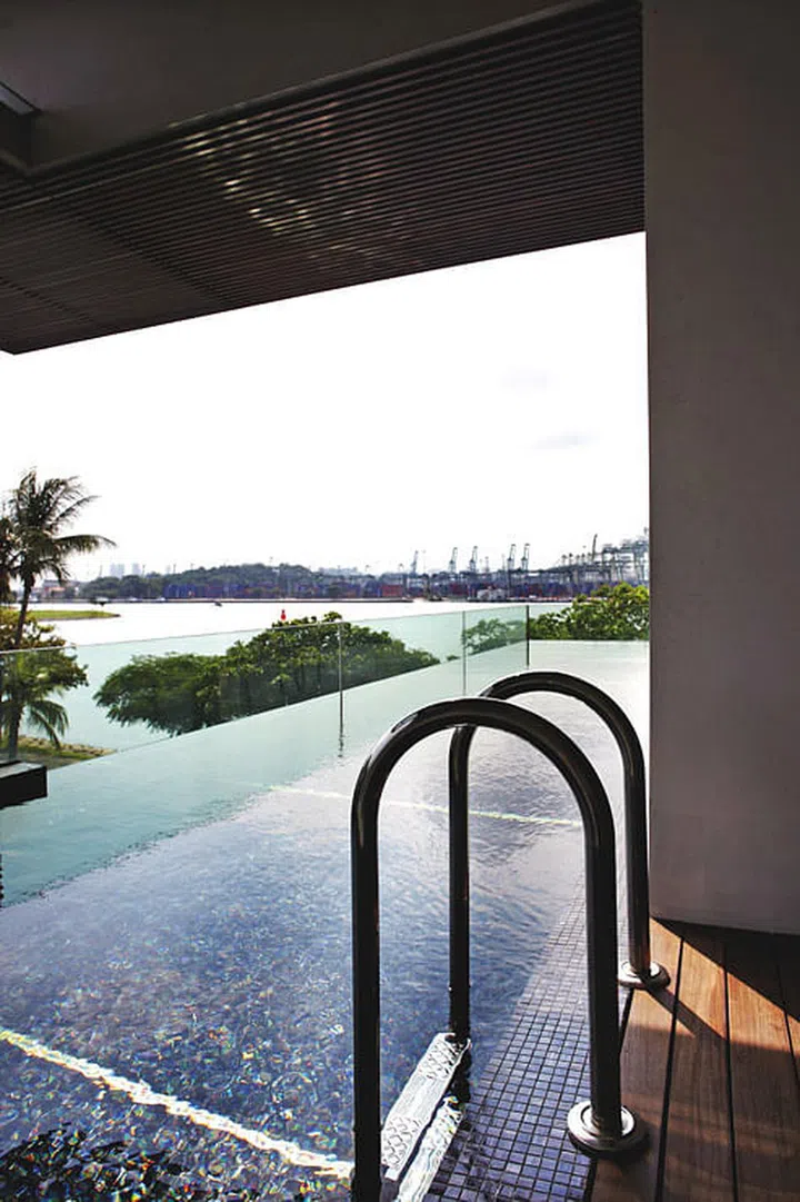 The rooftop lap pool in this 2.5-storey Sentosa Cove bungalow is bounded by tempered glass panels for an infinity-style finish.