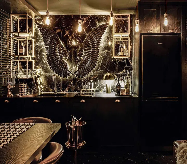 Naked bulbs, gold fittings and open shelves make for a dramatic, luxe and sexy bar ambience. Seashell-shaped cabinet handles reinforce the art deco theme. 
