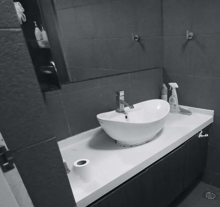 A sink with black tiles in the background