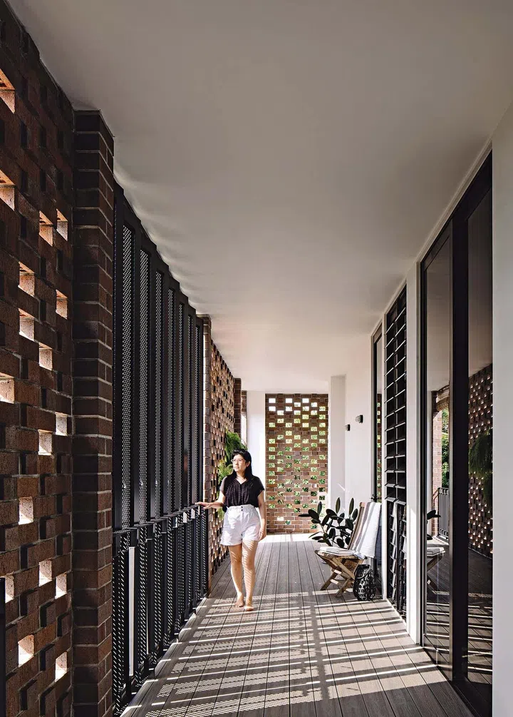 A lady walking along perforated brick walls