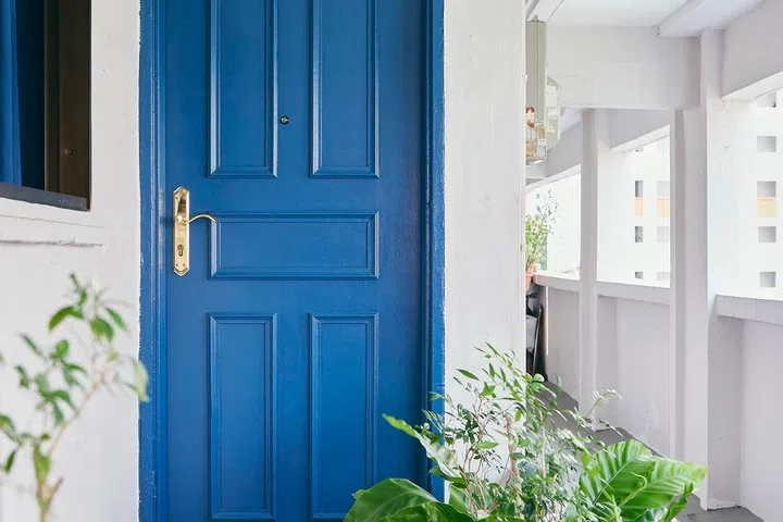 The distinctive blue door sets a welcoming tone amid the corridor’s lush greenery.