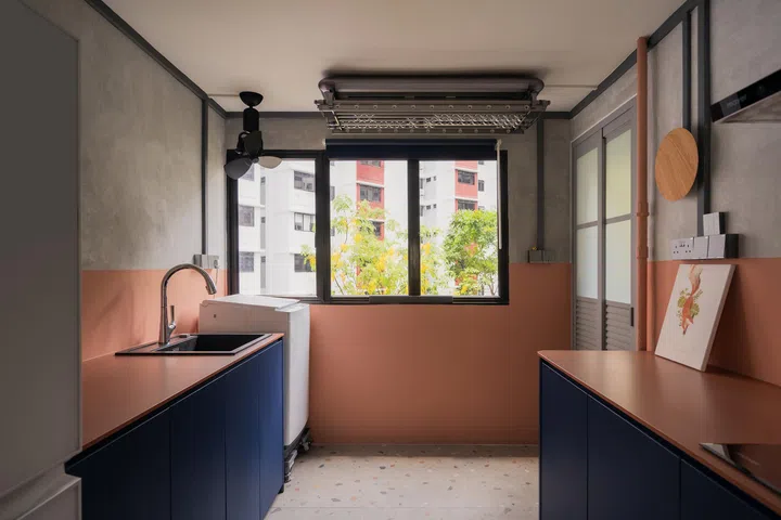 Cinnamon red counters and blue cabinetry pop against cement screed walls and terrazzo flooring, making the utilitarian space playful.