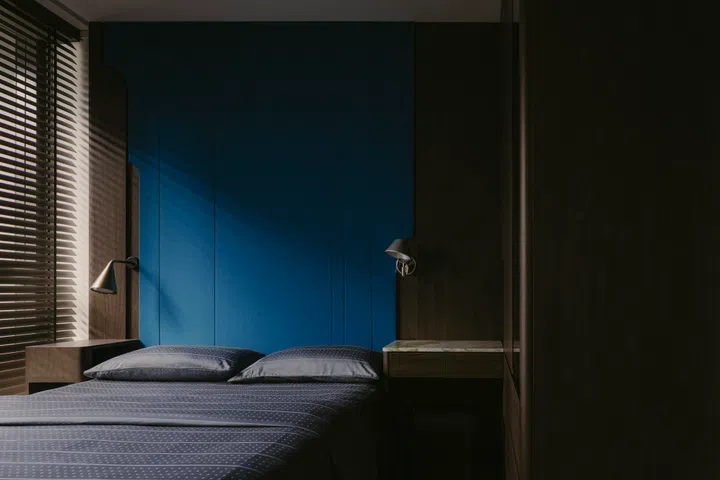Dark timber joinery and a blue upholstered headboard set a calm, restrained tone in the master bedroom.