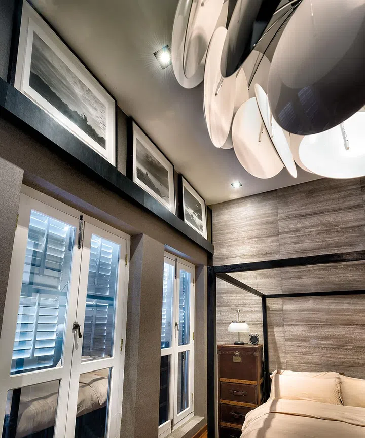 Black and white photography prints rest on the master bedroom's curtain pelmet.
