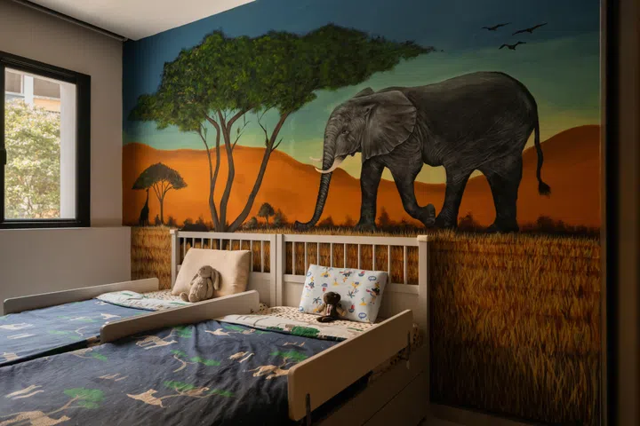 Hand-painted by their designer Zee, the safari mural transforms the children’s bedroom into an immersive landscape inspired by the African savannah.