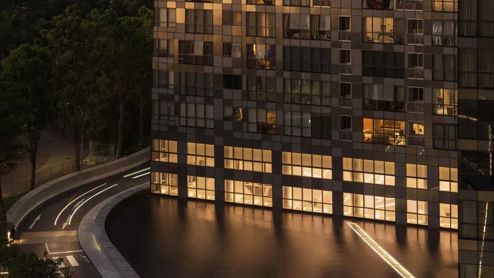 At dusk, the reflective façade of Reflections at Keppel Bay mirrors the warm glow of the family’s apartment within.