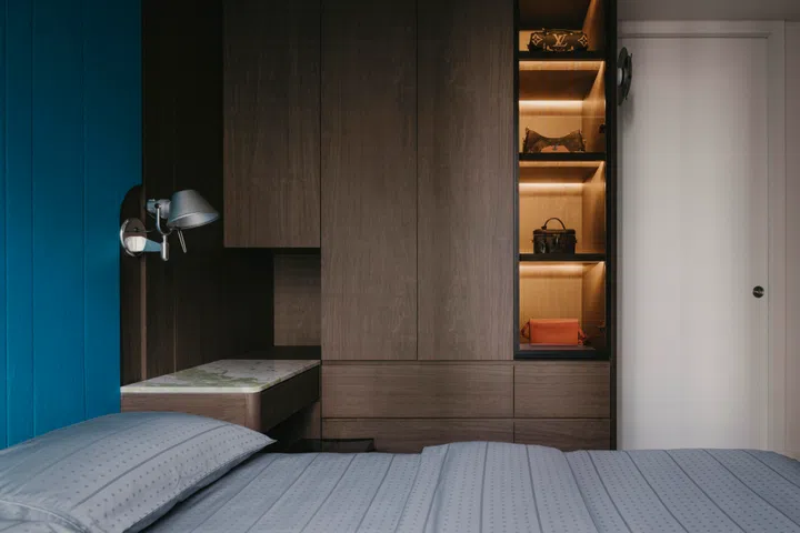 A softly lit display niche breaks up the wardrobe wall, adding warmth without disrupting the room’s quiet palette.