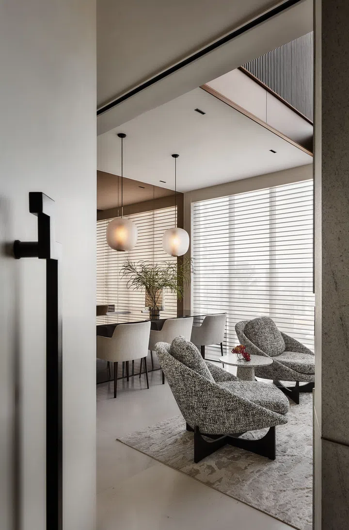The stone clad walls of the private lift lobby open up to a neutral pastel interior with a touch of bronze and highlights of matte and polished surfaces.