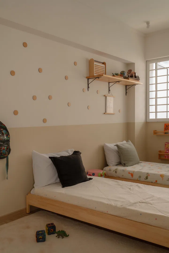A simple children’s bedroom is kept light and flexible, with low beds and open wall shelving for everyday play and rest.