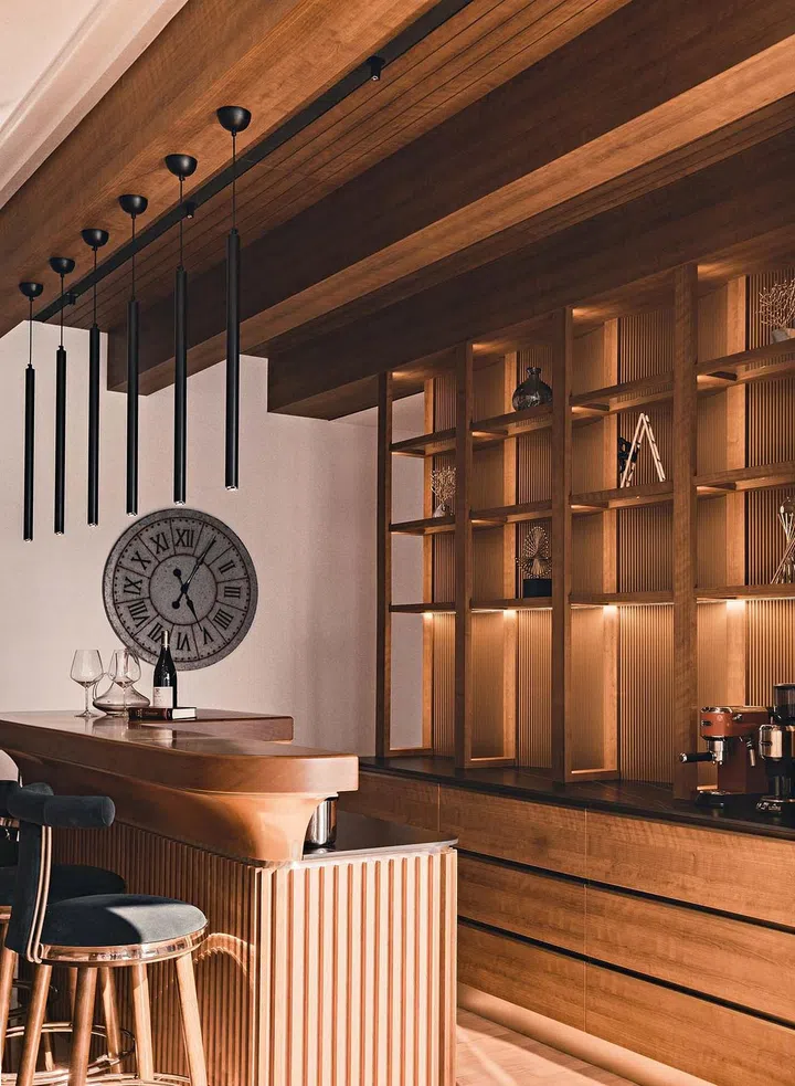 The curved lines of the bar counter, rich wood hue, fluted panels and plush bar stools with metallic details give the space an Art Deco touch.