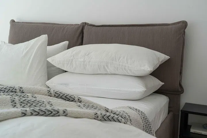 How to Sleep Better? An Ear Nose Throat Doctor Shares Expert Tips. Pillows stacked on a mattress and duvet