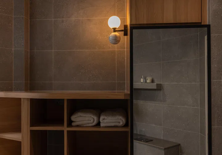 Integrated carpentry conceals storage behind mirrors and walls, keeping the washbasin area clean and deliberately composed.
