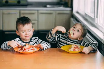 Boy and girl in the kitchen eating pasta. Photo 123RF