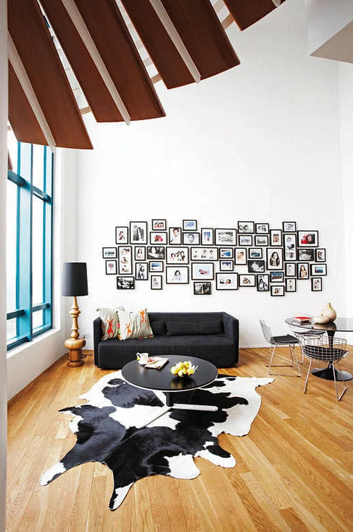 An eclectic arrangement of family photo frames above the sofa in the living room of a high ceiling double volume unit. Interior design by Frame Interior.