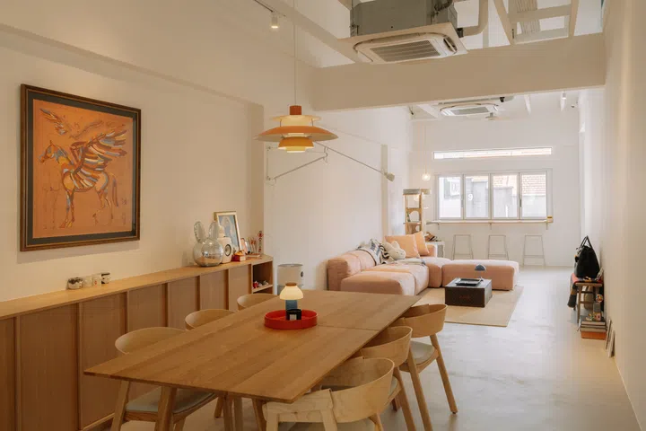 Looking across the dining room towards the living area, the open-plan layout and exposed roof structure reveal the dramatic sense of volume created by the renovation.