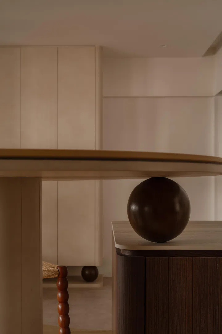 A wooden sphere physically and visually links the island and bar table, reinforcing the home’s curved language.