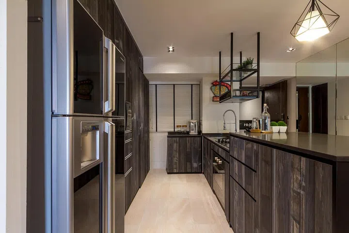 A weathered wood-look laminate was chosen for the cabinetry here, to lend the open-concept kitchen a rustic and industrial touch. Interior design by Fineline.