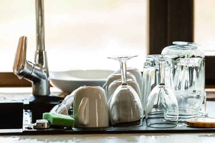 Washing up. Modern sink and kitchen counter with claen dishwares, window in the background