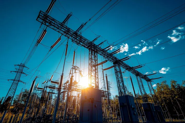 High voltage transformer and electrical equipment against a bright blue sky in realistic photography