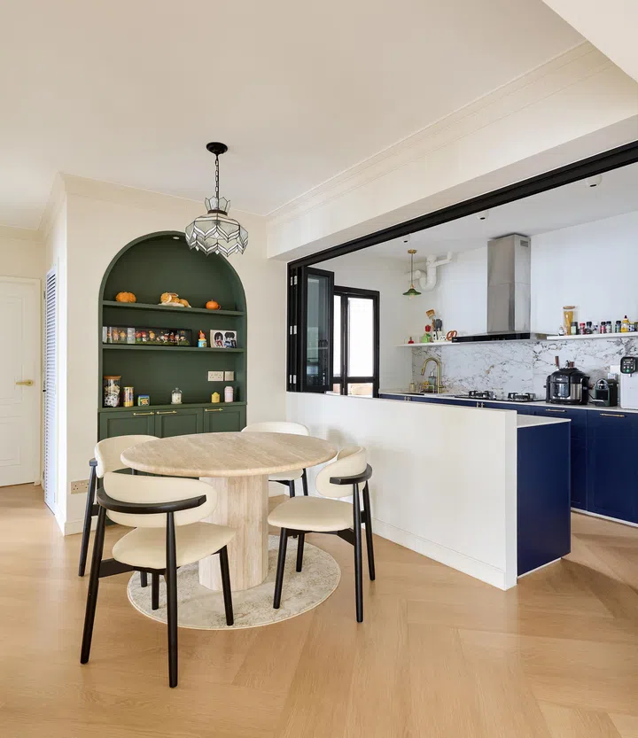 The kitchen opening to the dining area in front here in a 5-room HDB in Tengah, designed by Jeremy from RENOSTUD.IO.