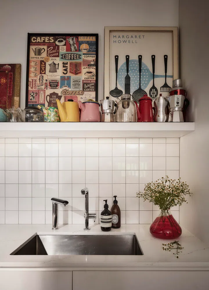 Open shelves display coffee tools, teapots, and daily-use objects, reflecting the homeowners’ belief that living with visible, well-used items makes the kitchen feel more mindful and lived in.