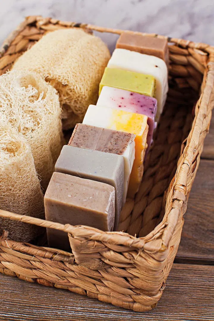 Basket with different handmade soap bars and loofah for body care. Eco friendly products and cosmetics