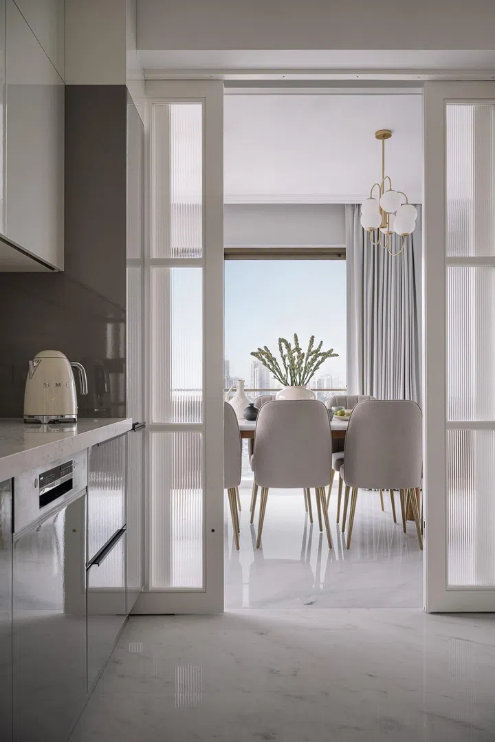 White marble flooring runs throughout the kitchen and dining room in this 2-bedroom apartment in Parsi, Mumbai.