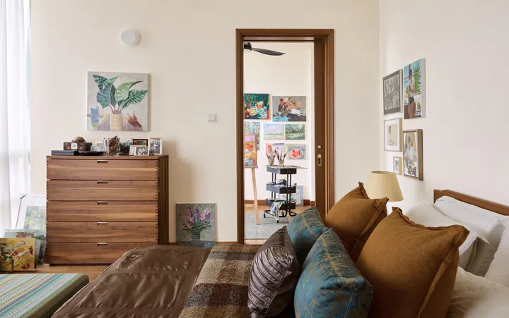 A view from a personal bedroom revealing part of an adjacent art studio through an open doorway.