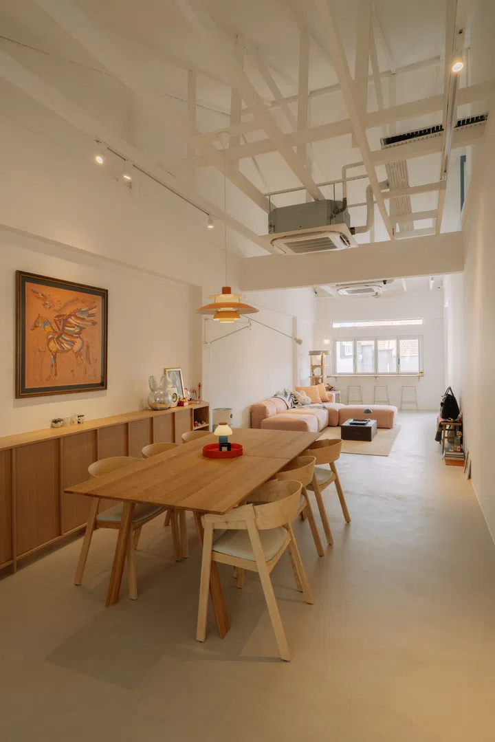 Looking across the dining room towards the living area, the open-plan layout and exposed roof structure reveal the dramatic sense of volume created by the renovation.