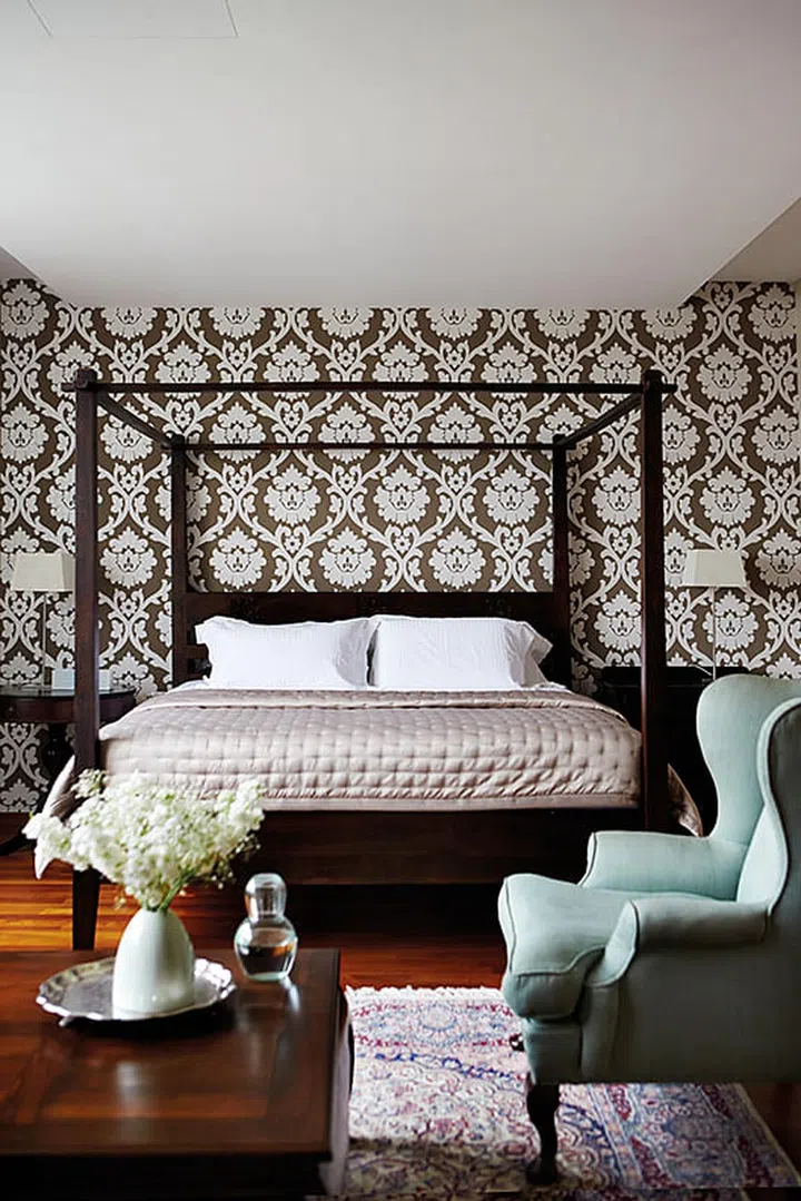 The master bedroom enjoys a dash of old world glamour, thanks to the Rococo-style wallpaper and the couple's classic furniture collection.