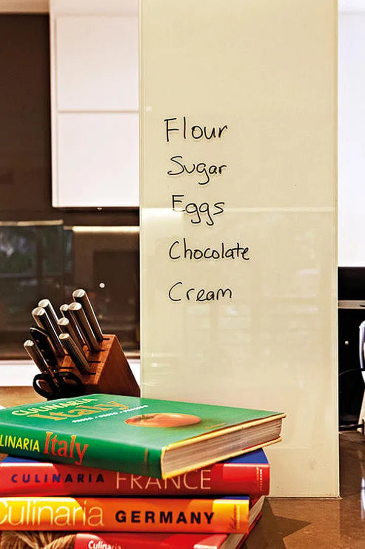 This designer decided to turn it into a feature, building a countertop around the pillar and cladding it in glass for the owners to use as a whiteboard. (Interior design by Dwell Interior Design)