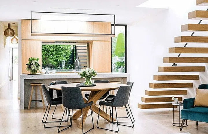 Round dining table modern Scandinavian interior design with grey modern chairs and an open floating wood staircase