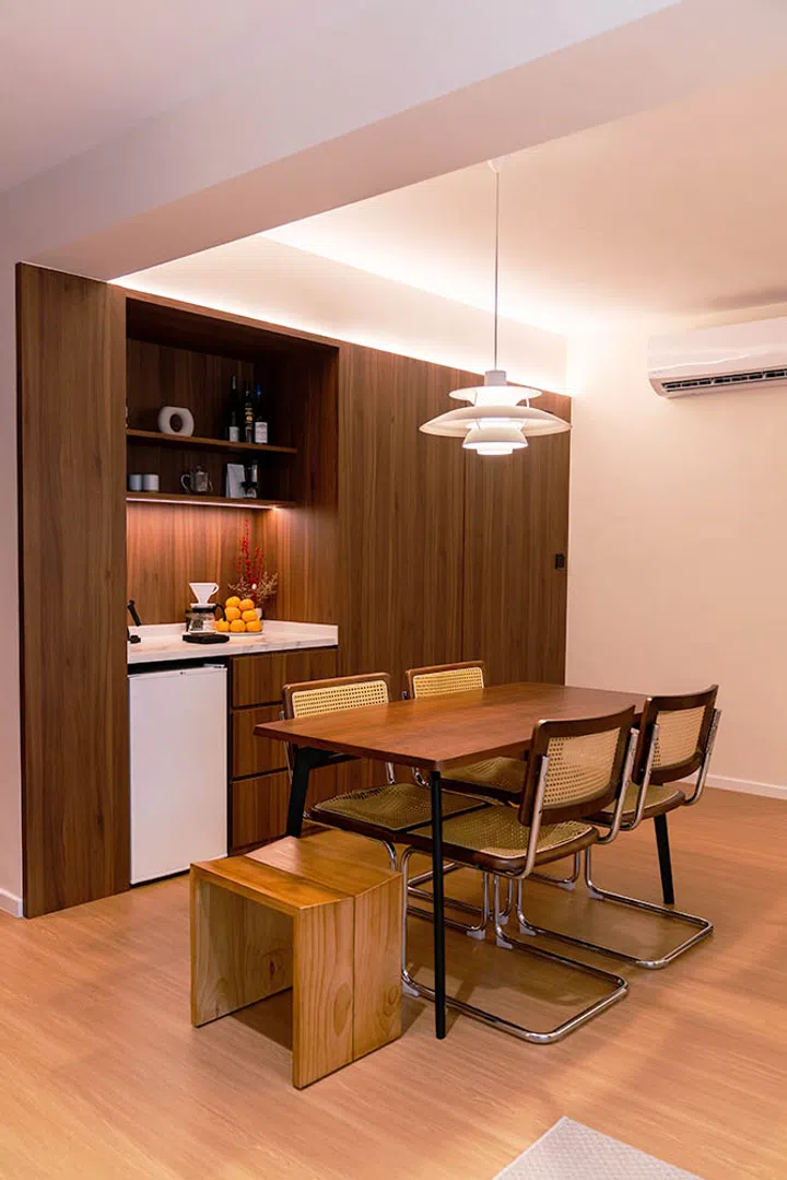 The dining area is anchored by a wooden table and modern dining chairs, with rattan accents that add warmth and texture to the space.