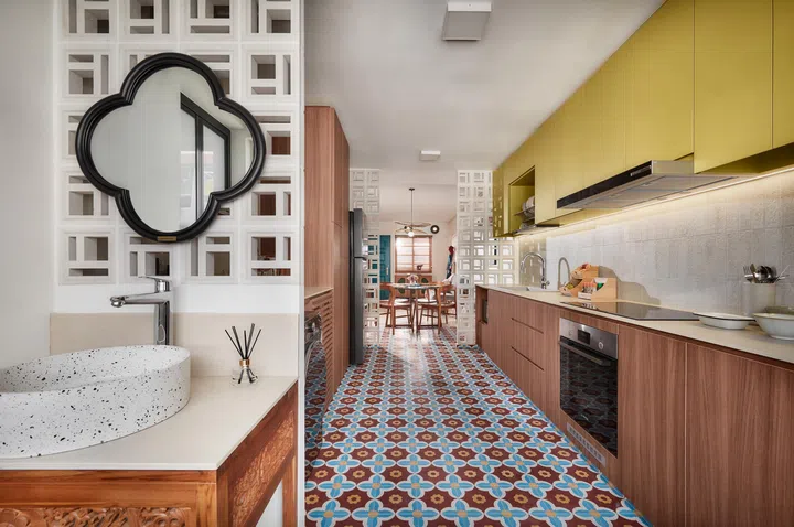 Patterned tiles extend into the kitchen, echoing the geometric rhythm of the breeze blocks and curved forms throughout the space.